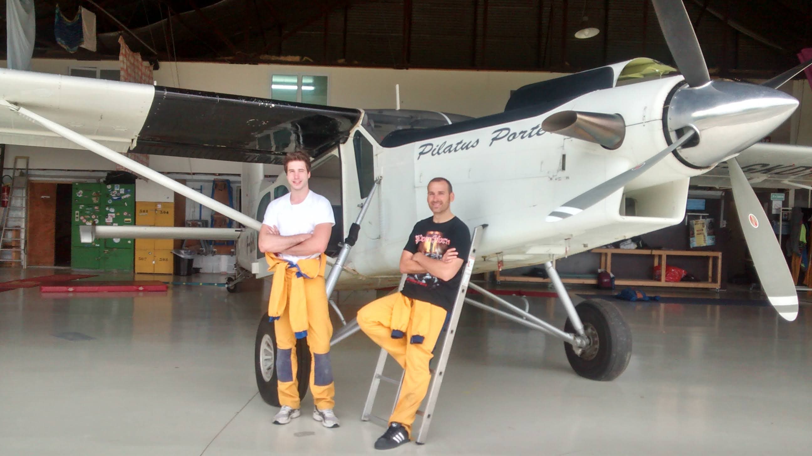 Photo of Anthony, the owner of the website, and his friend, in skydiving training uniforms, posing in front of a small size airplane used for skydiving